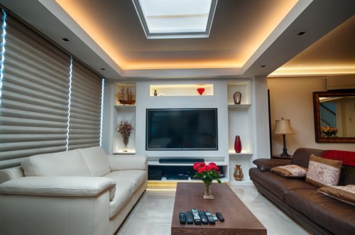 Living room with LED tape in lowered ceiling and shelves with adjustable trimless downlights in bulkhead